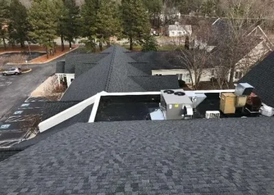An aerial view of a large property with dark asphalt shingle roofs and flat roof sections in Richmond, VA.