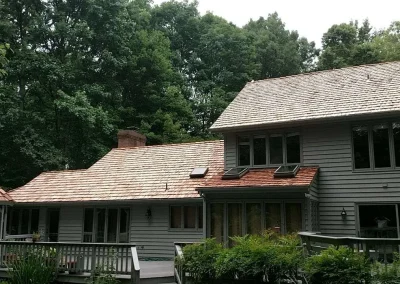 Two-story residential house with a prominent, newly installed roof made of cedar shakes.