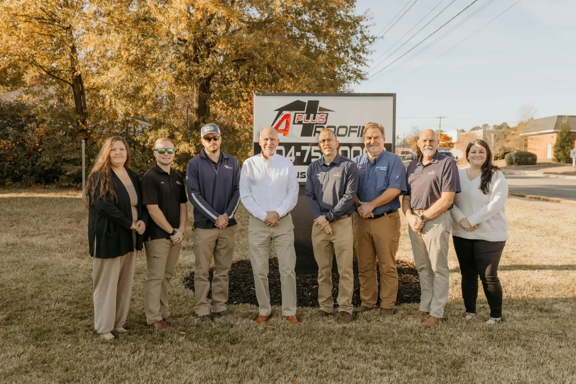 The professional team of roofers in Short Pump, VA from A Plus Roofing standing together in front of their company sign.