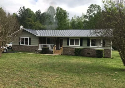 A ranch-style house featuring a stone veneer base and a newly installed grey metal roof, completed by expert roofers in Short Pump, VA.